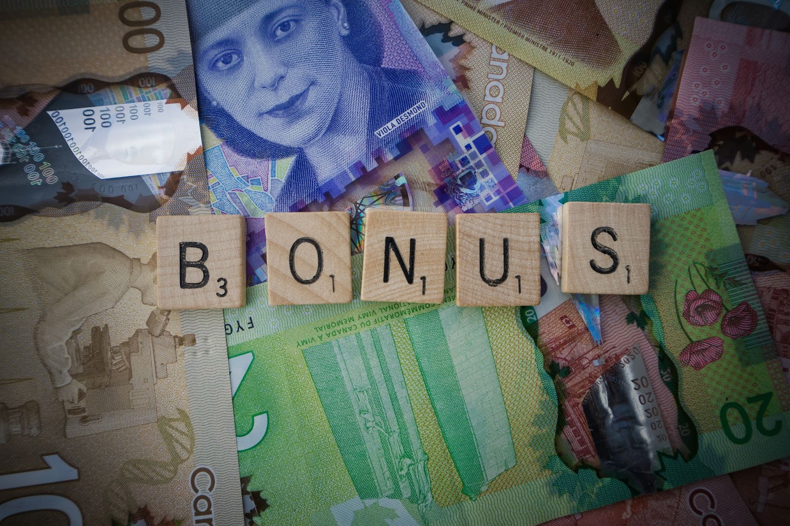 The word 'Bonus' spelled out in Scrabble tiles on a collage background